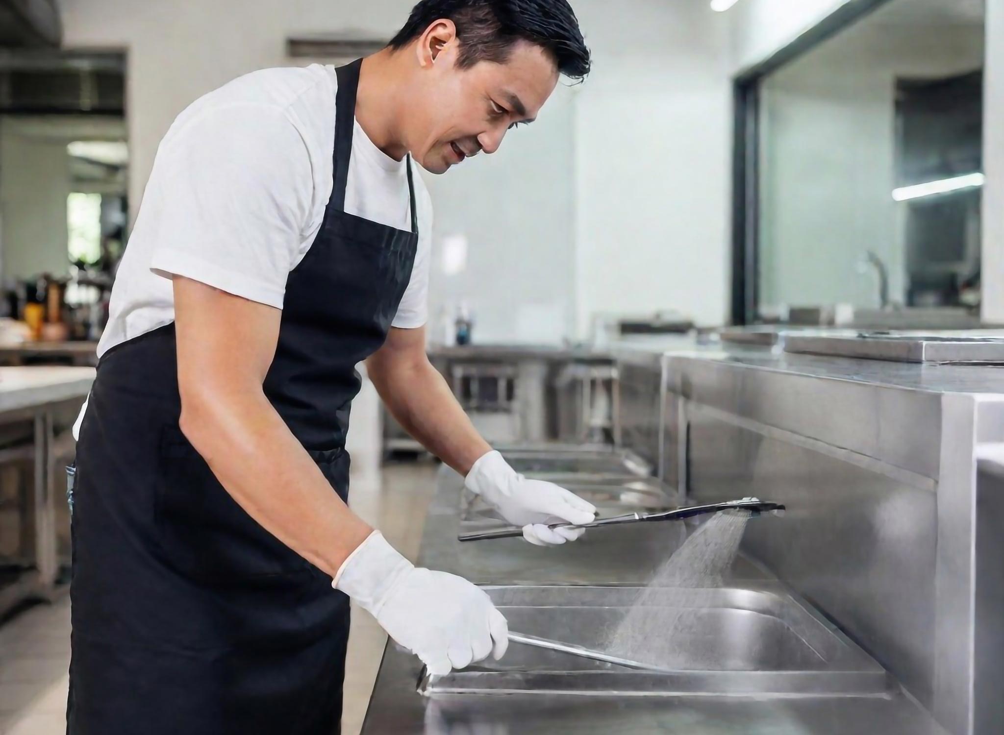 A professional cleaner doing a grease trap cleaning in a restaurant.